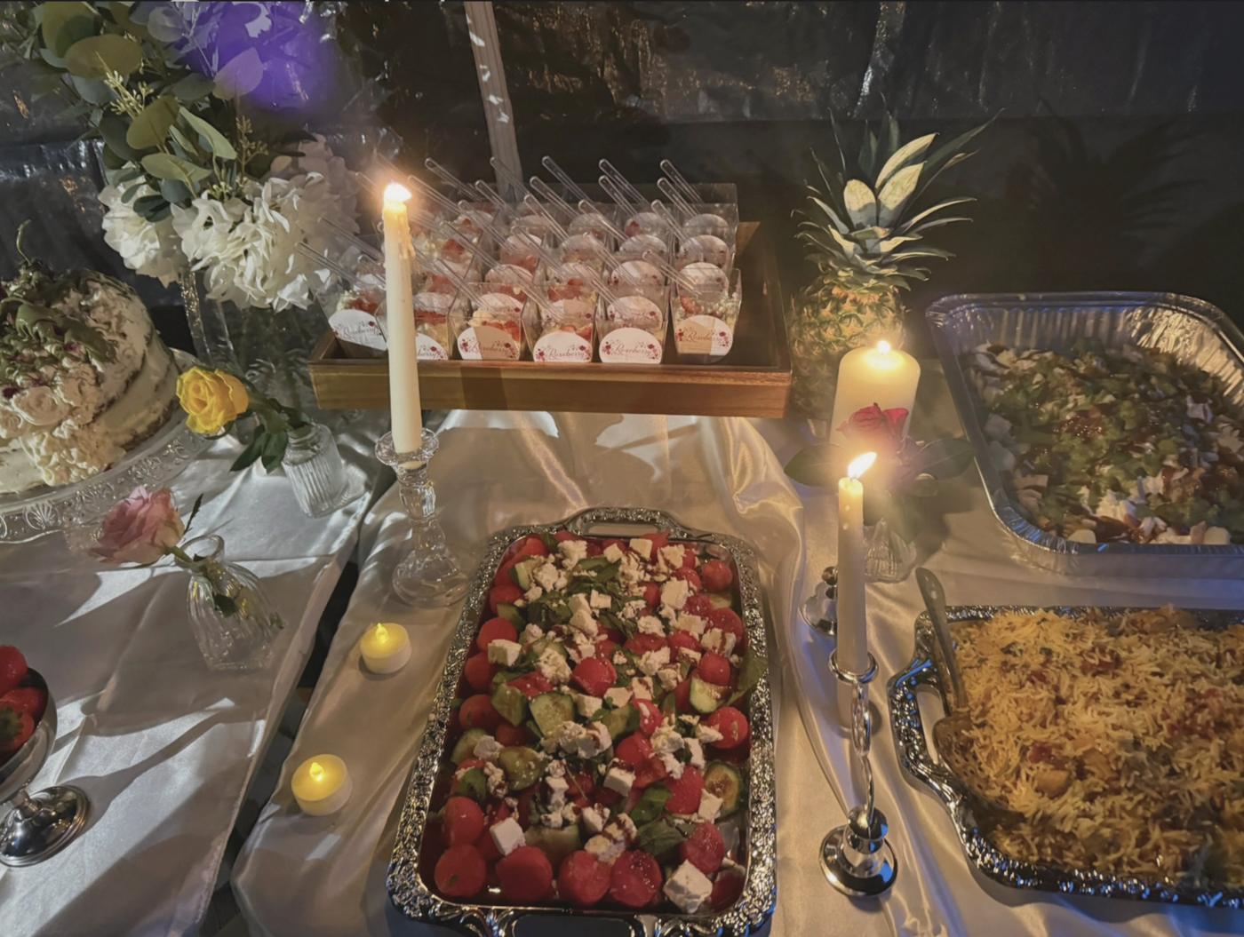 A candlelit Roseberry table with salads, rice, cake and branded desserts